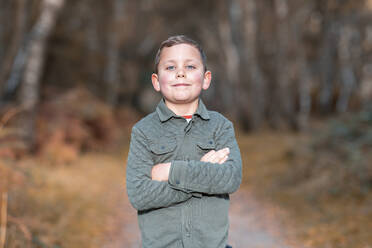 Junge mit verschränkten Armen im Herbst im Park stehend - WPEF03562