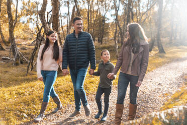 Familie, die sich gegenseitig anschaut, während sie im Herbst im Park spazieren geht - WPEF03567