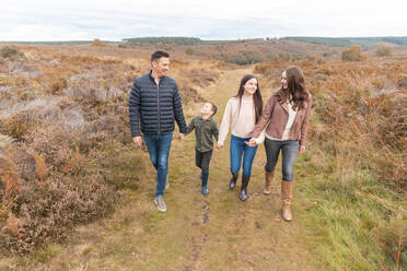 Parents holding hands of children walking in park during autumn - WPEF03579