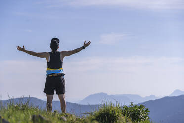 Carefree man standing with arms outstretched on mountain - SNF00758