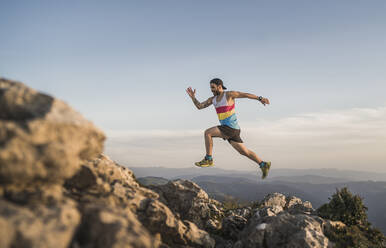 Athlete running on mountain against clear sky during sunset - SNF00782