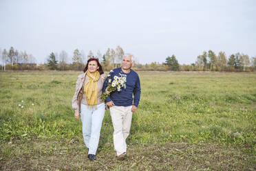 Älteres Paar mit Blumen auf einem Feld gegen den Himmel - EYAF01386