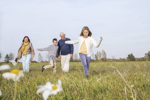 Grandparents with grandchildren spending leisure time on field against sky during weekend stock photo