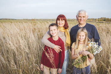 Happy grandparents and grandchildren standing at field - EYAF01406