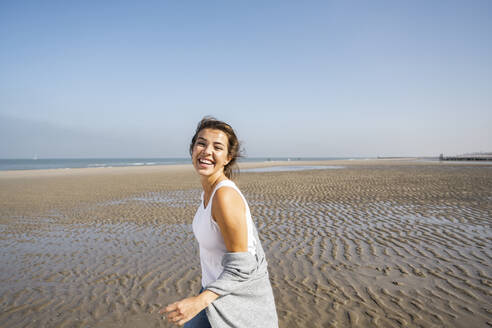 Happy young woman at beach against clear sky during sunny day - UUF22014