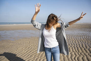 Glückliche junge Frau tanzt am Strand gegen den klaren Himmel an einem sonnigen Tag - UUF22020