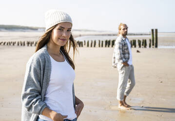 Smiling young woman with man at beach during sunny day - UUF22027