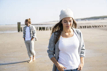 Nachdenkliche Frau mit Händen in den Taschen am Strand an einem sonnigen Tag - UUF22030