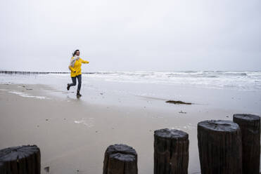 Sorglose reife Frau läuft am Strand gegen den Himmel - UUF22055