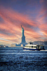 Freiheitsstatue und Boot auf dem Hudson River gegen den Himmel bei Sonnenuntergang, New York, USA - HOHF01426