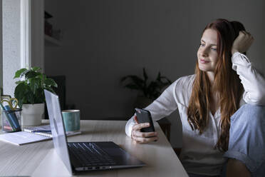 Smiling psychologist using mobile phone while sitting at home - AFVF07446