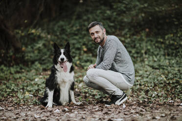 Man crouching by dog at public park - GMLF00790