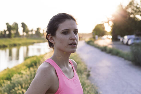 Selbstbewusste Sportlerin, die bei Sonnenuntergang im Park steht und wegschaut - SBAF00051