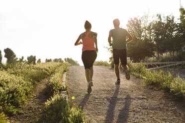 Fit junges Paar joggt im Park bei Sonnenuntergang - SBAF00061