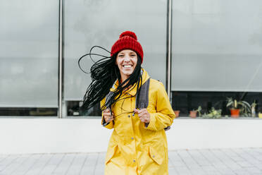 Woman wearing yellow raincoat standing on street - EBBF01226