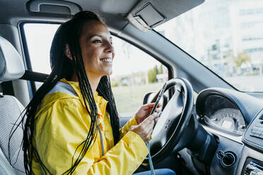 Frau benutzt Smartphone im Auto sitzend während einer Autofahrt - EBBF01233