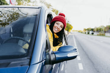 Lächelnde Frau lehnt sich während einer Autoreise an ein Autofenster - EBBF01241