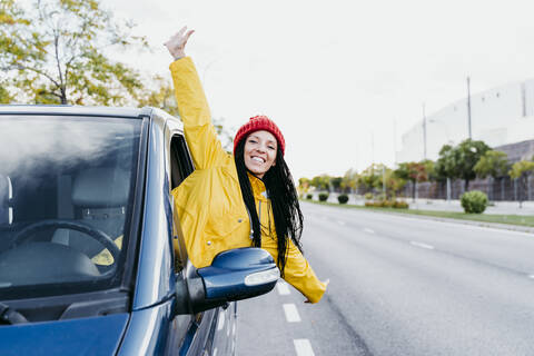 Carefree woman with arms outstretched leaning out of car stock photo