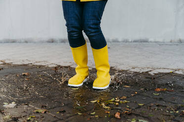 Frau mit gelben Stiefeln springt auf die Straße - EBBF01247