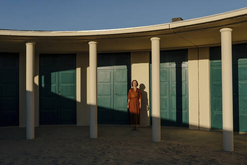 Mittlere erwachsene Frau steht vor einer Tür in einem Ferienort in Deauville, Frankreich - OGF00661