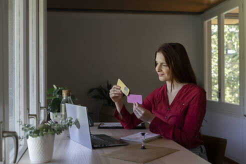 Psychologist showing paper on video call while sitting at home - AFVF07447