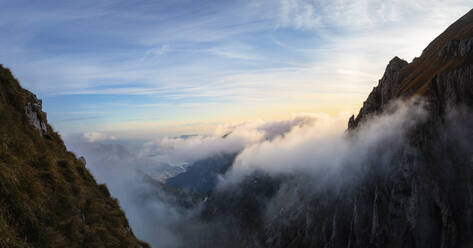 Idyllische Aufnahme eines von Wolken bedeckten Berges bei Sonnenaufgang in den Bergamasker Alpen, Italien - MCVF00643
