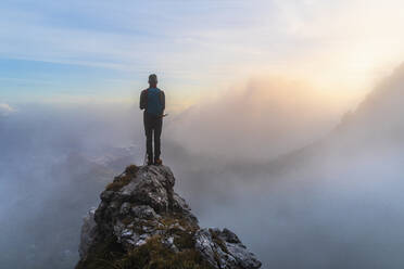 Nachdenklicher männlicher Wanderer auf einem Berggipfel bei Sonnenaufgang in den Bergamasker Alpen, Italien - MCVF00646