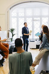 Businessmen discussing strategy with colleagues at workplace - JRFF04818