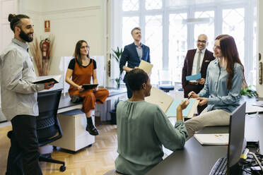 Smiling entrepreneurs discussing business strategies at workplace - JRFF04825