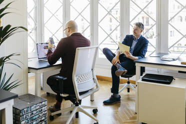 Geschäftsleute arbeiten am Schreibtisch vor dem Fenster im Büro - JRFF04828