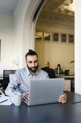 Hipster businessman working on laptop at workplace - JRFF04848