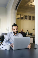 Hipster-Geschäftsmann arbeitet am Laptop am Arbeitsplatz - JRFF04848