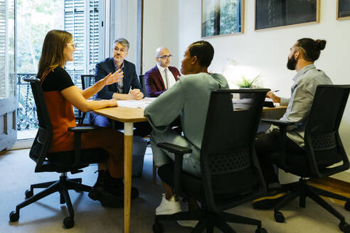 Businesswoman discussing with coworkers at table in office - JRFF04902