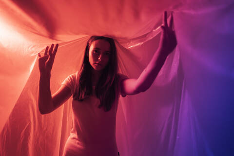 Young woman with hand raised lost in plastic maze during COVID-19 stock photo