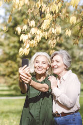 Reife Frau, die Selfie durch Handy mit Freund beim Stehen im Park in der Stadt - VYF00230