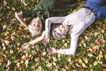 Unbekümmerte Frauen lächelnd im Gras liegend im Park - VYF00234