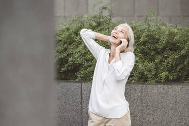 Cheerful talking on mobile phone while standing at city - VYF00271