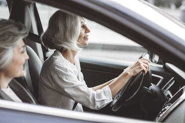 Lächelnde Geschäftsfrauen, die zusammen im Auto reisen - VYF00276