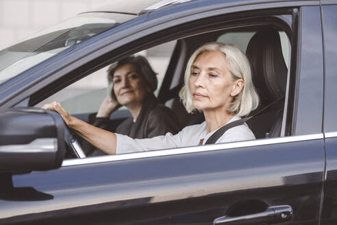 Businesswoman sitting with colleague driving car in city - VYF00278