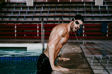 Junger Schwimmer ohne Hemd, der sich an den Beckenrand lehnt - EBBF01293