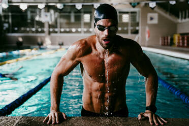 Professioneller muskulöser männlicher Schwimmer, der aus dem Pool steigt - EBBF01294