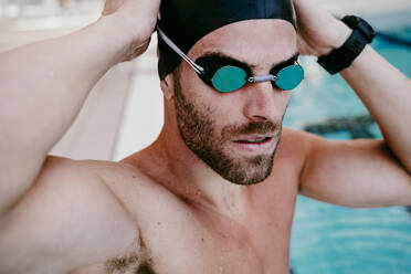 Gut aussehender männlicher Schwimmer beim Einstellen der Schwimmbrille - EBBF01310