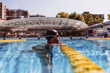 Männlicher Schwimmer an der Bahnmarkierung im Schwimmbad - EBBF01316