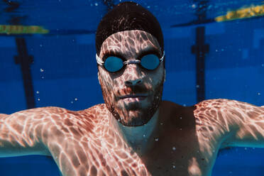 Junger männlicher Schwimmer schwimmt unter Wasser im Pool - EBBF01319