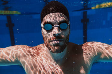 Young male swimmer swimming underwater in pool - EBBF01319