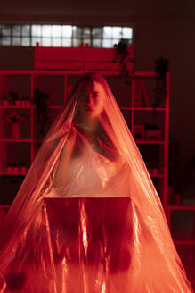 Young woman with laptop covered in plastic during pandemic - GIOF09545