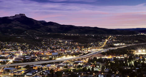 USA, Colorado, Trinidad, Interstate 25 durch beleuchtete Stadt bei Nacht mit Fishers Peak im Hintergrund - BCDF00514