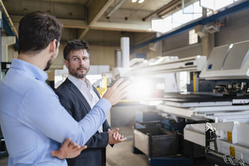 Geschäftsleute im Gespräch mit einem Kollegen in einer modernen Fabrik - DIGF12991