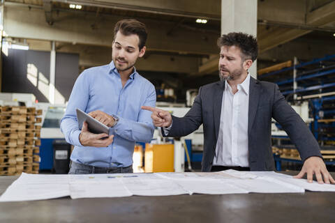 Businessmen using digital tablet while working at factory stock photo