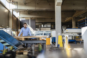 Geschäftsmann bei der Arbeit an einem Tisch in einer Fabrik - DIGF13007